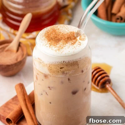 A glass filled with an iced salted honey latte on a serving board.