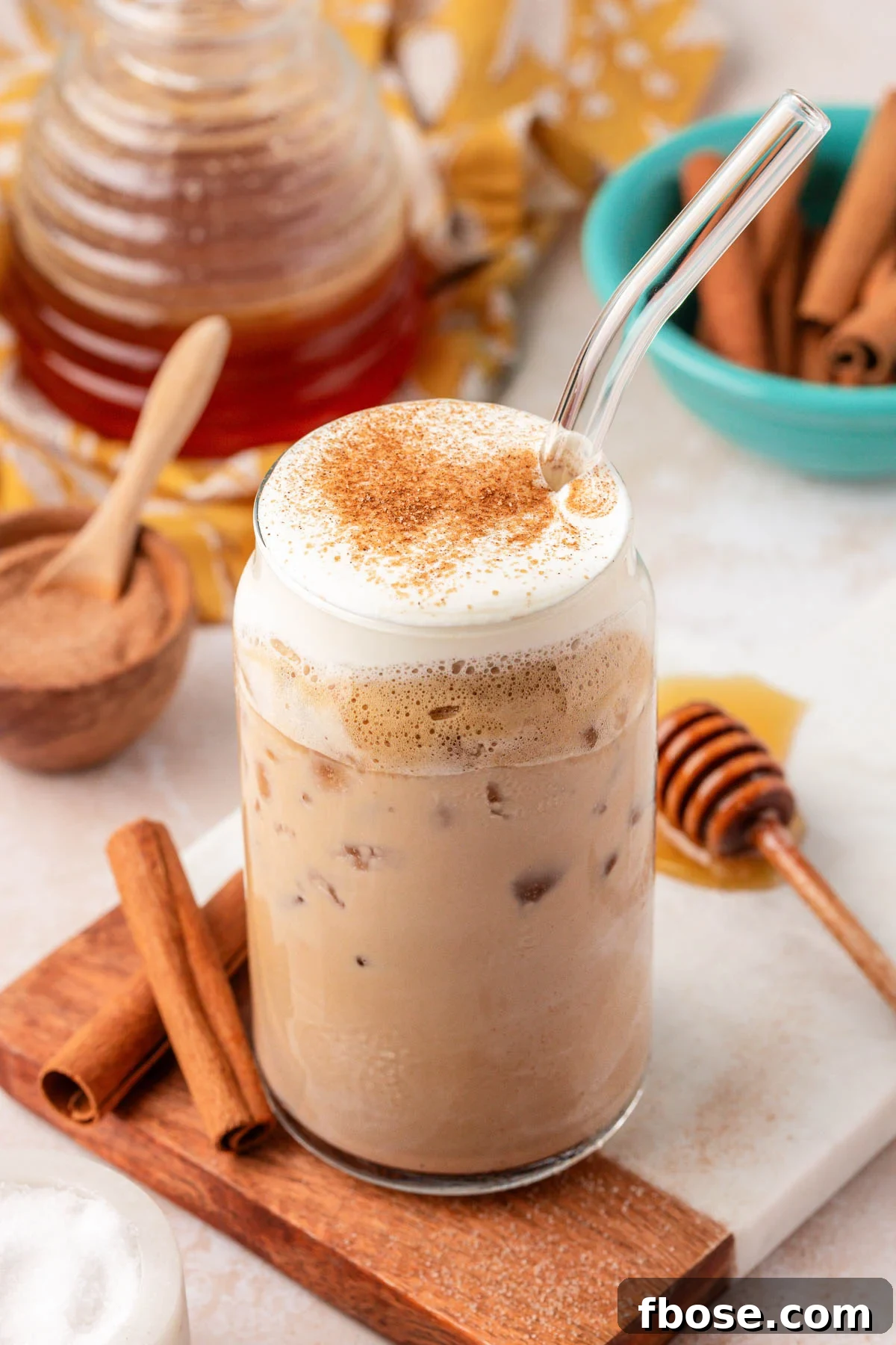A glass filled with an iced salted honey latte on a serving board.