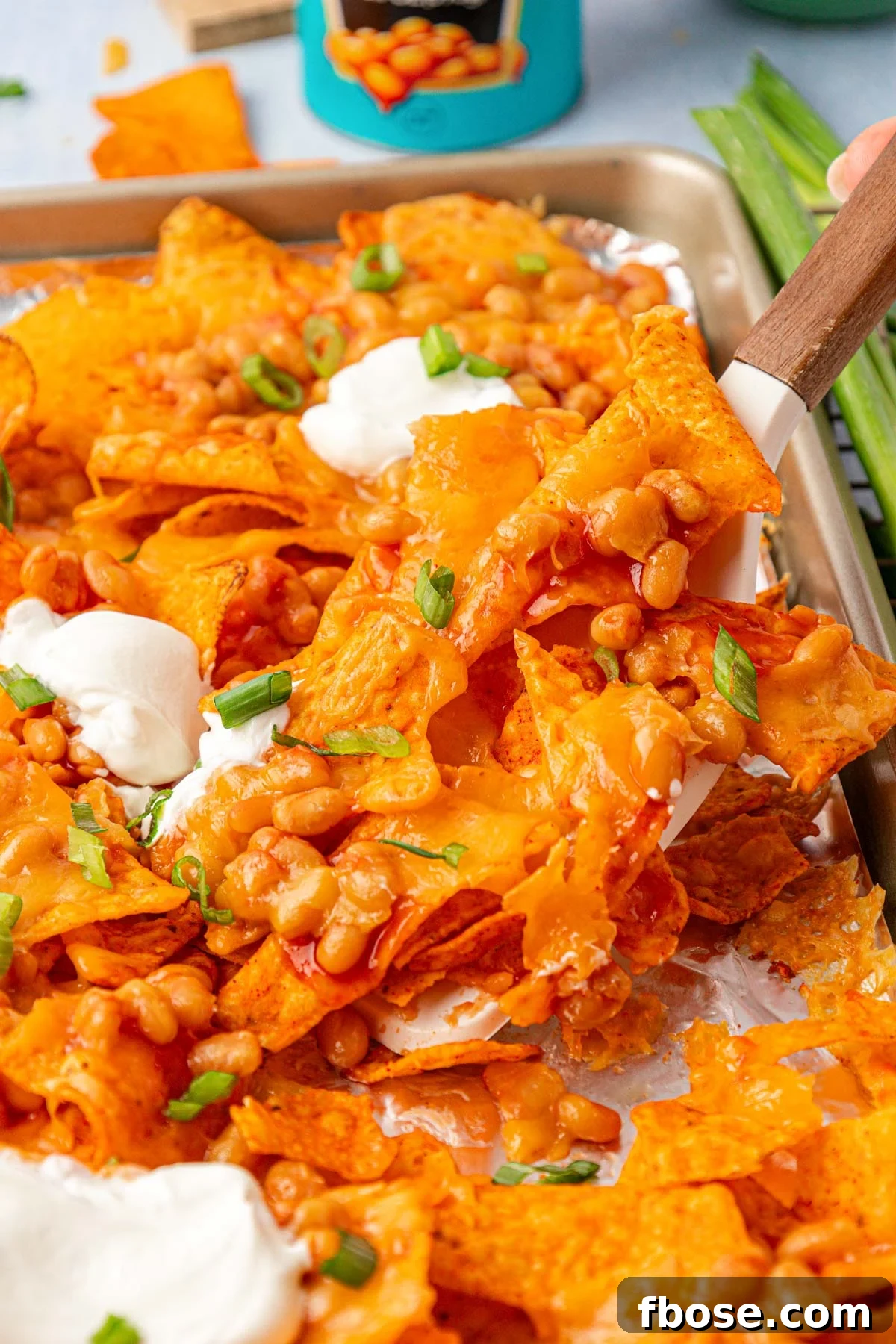 Margot Robbie's Bean Nachos being lifted off a pan with a spatula.