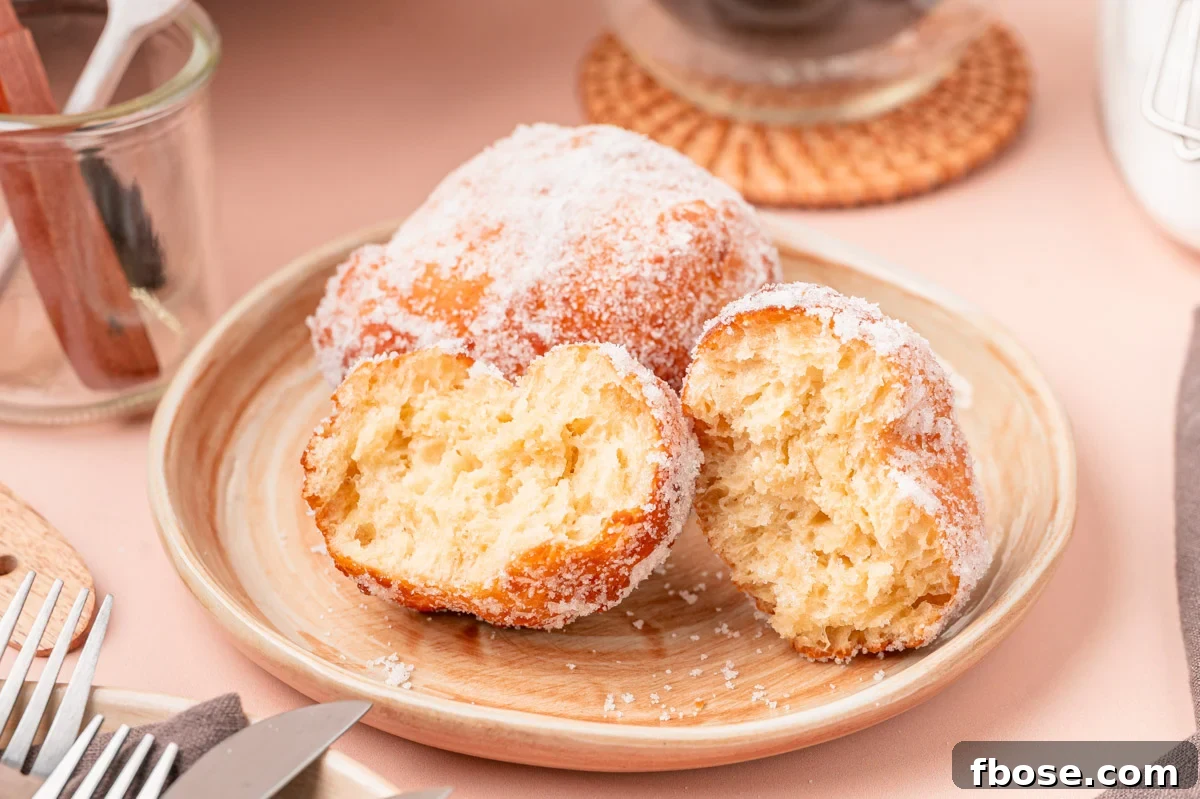 Close up of a plate on malasadas, one of them has been broken in half.