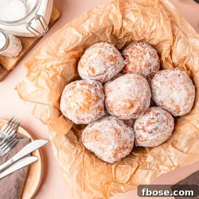 Overhead photo of Malasadas in a basket with parchment paper.