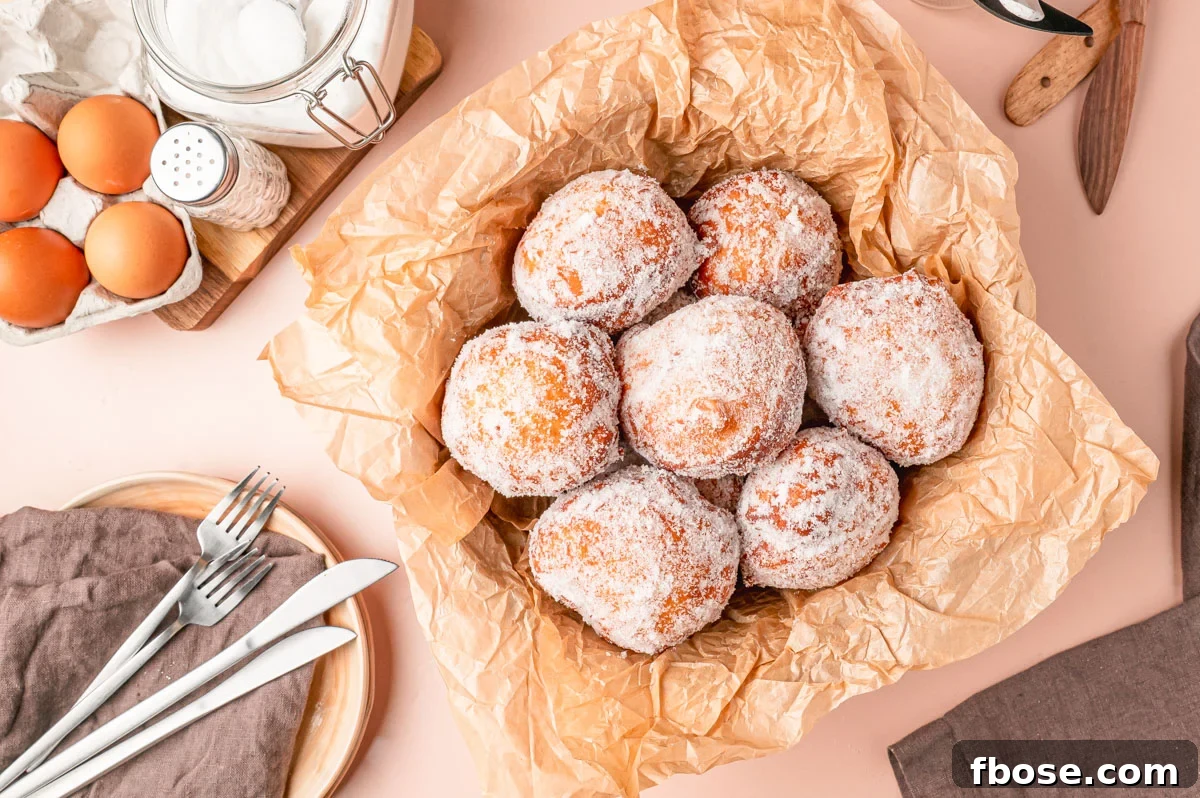 Overhead photo of Malasadas in a basket with parchment paper.